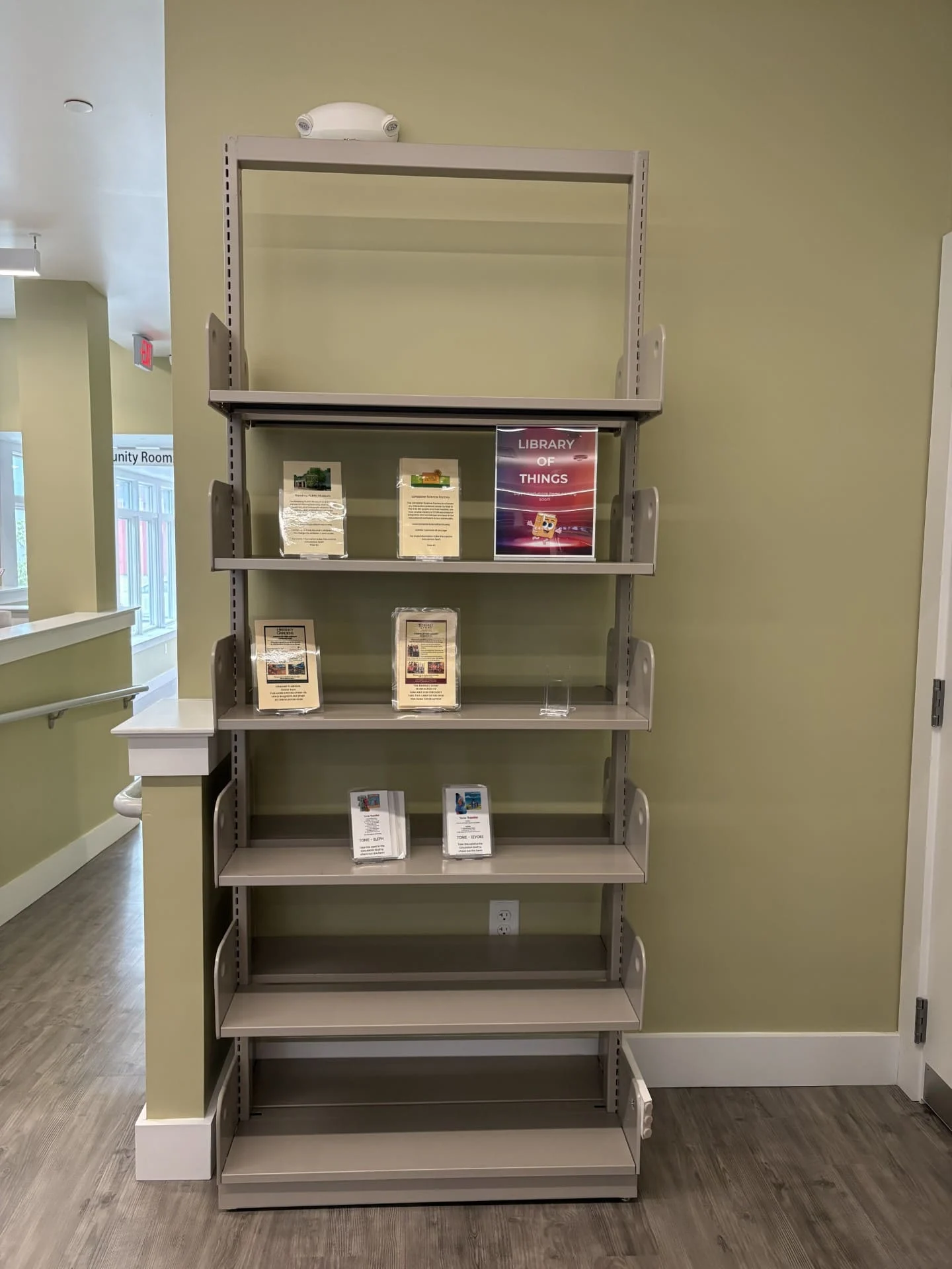 A metal shelf with Library of Things items on the three middle levels of the shelf
